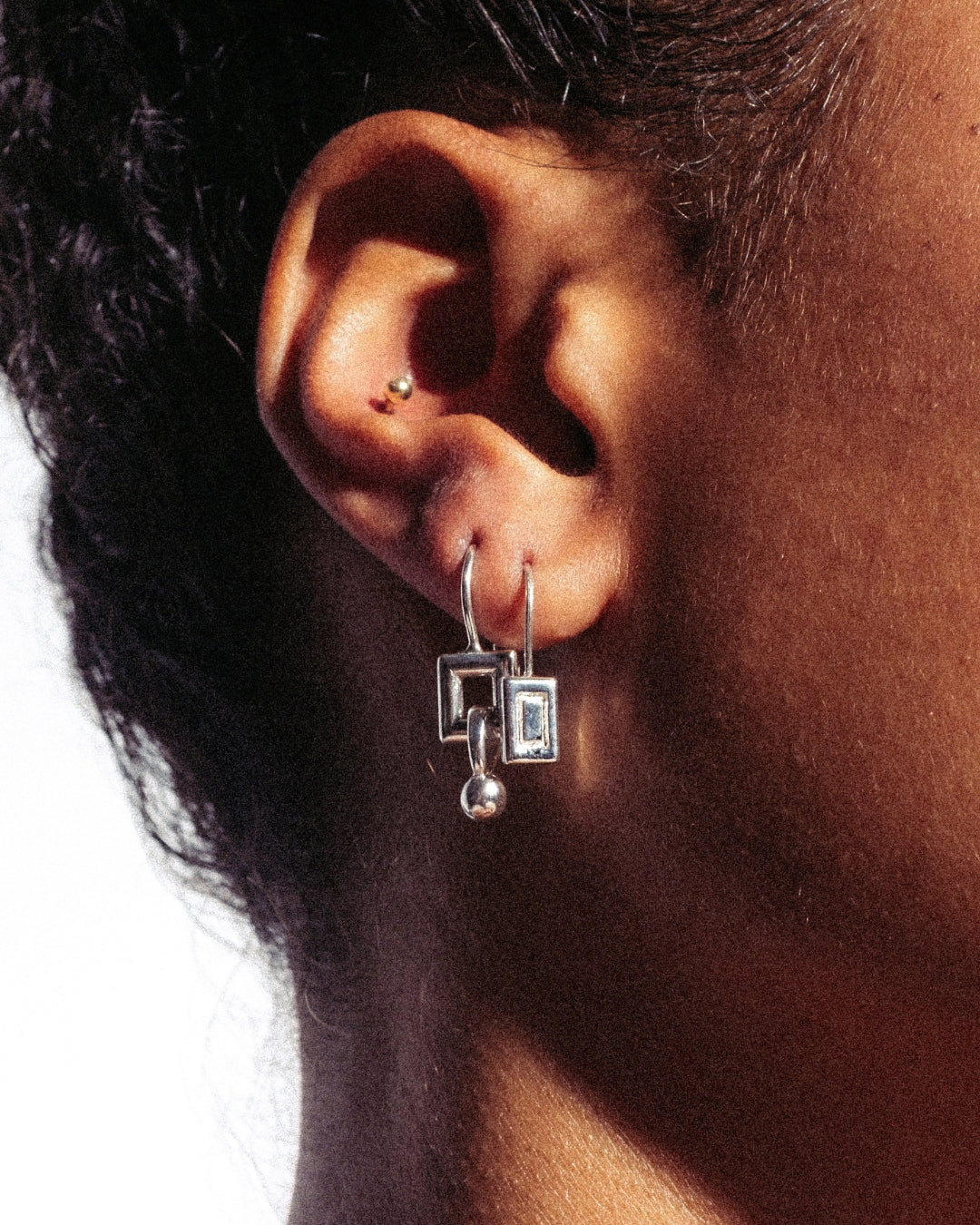 Ohrhänger aus 925er Silber mit rechteckigem Element, ovaler Verbindung und beweglicher Kugel am unteren Ende. Modernes, grafisches Design mit Hakenverschluss.