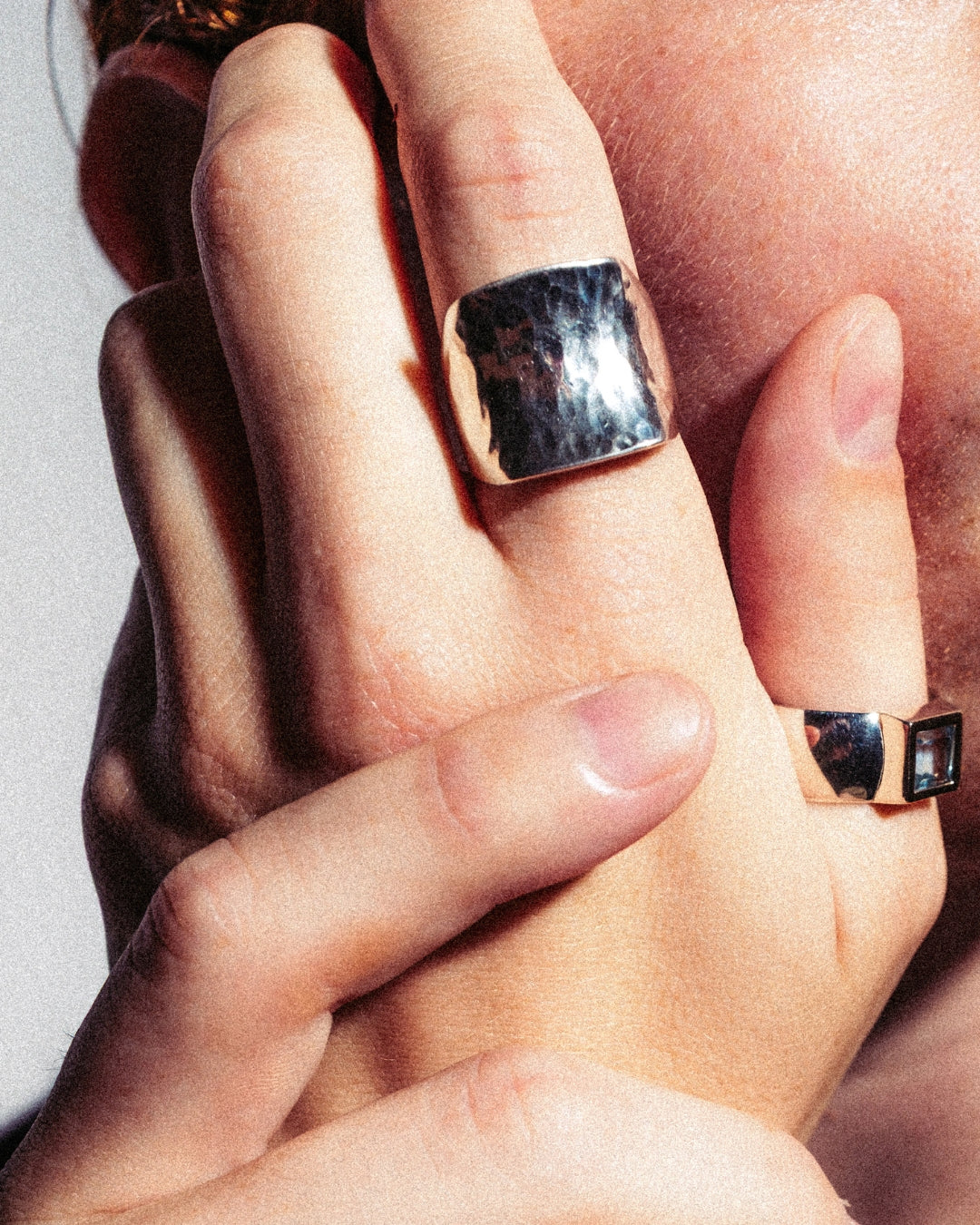 Breiter Ring aus 925er Silber mit gehämmerter, glänzender Oberfläche. Getragen an der Hand, das Licht spiegelt sich in der strukturierten Fläche. Moderner Unisex-Stil, lässig kombinierbar.