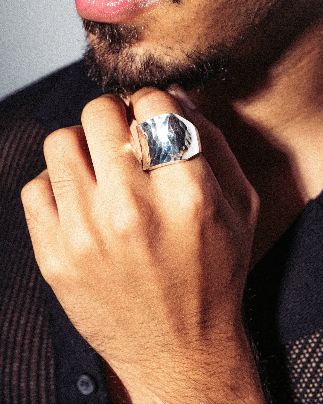 Breiter Ring aus 925er Silber mit gehämmerter, glänzender Oberfläche. Getragen an der Hand, das Licht spiegelt sich in der strukturierten Fläche. Moderner Unisex-Stil, lässig kombinierbar.